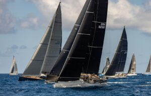 Sailboats race across the ocean on a bright day.